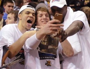 Wichita State's Ron Baker, center, takes a photo with Fred VanVleet, left, and Cleanthony Early, right, after their victory over Indiana State in an NCAA college basketball game in the championship of the Missouri Valley Conference men's tournament, Sunday, March 9, 2014, in St. Louis. (AP Photo/Bill Boyce)